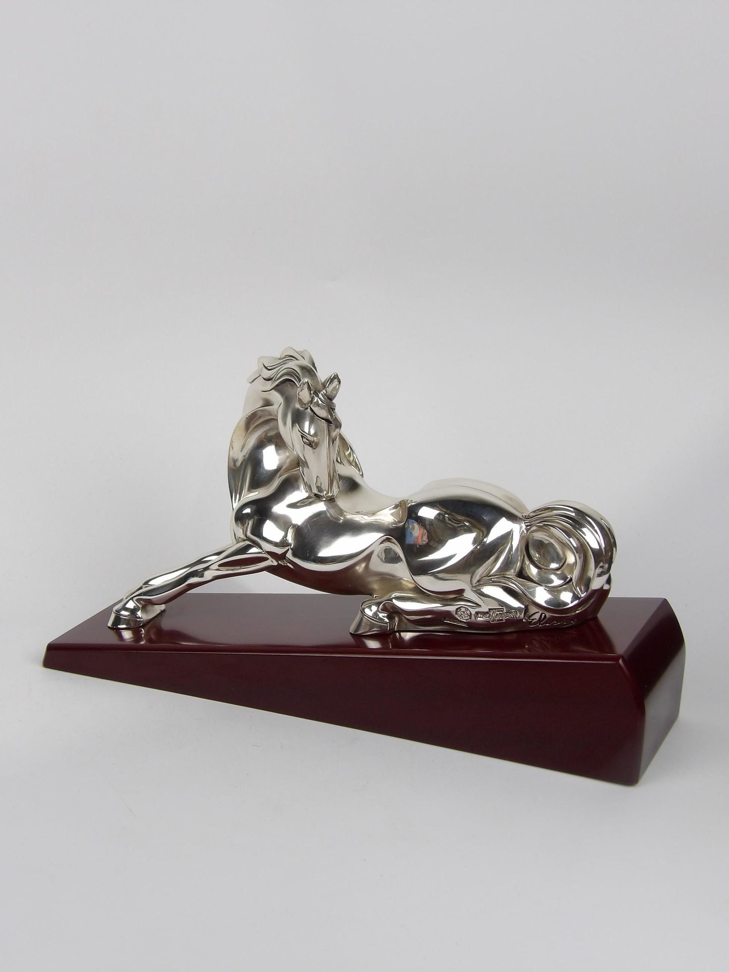 silver-coated resin sculpture on a mahogany base, with sitting horse
