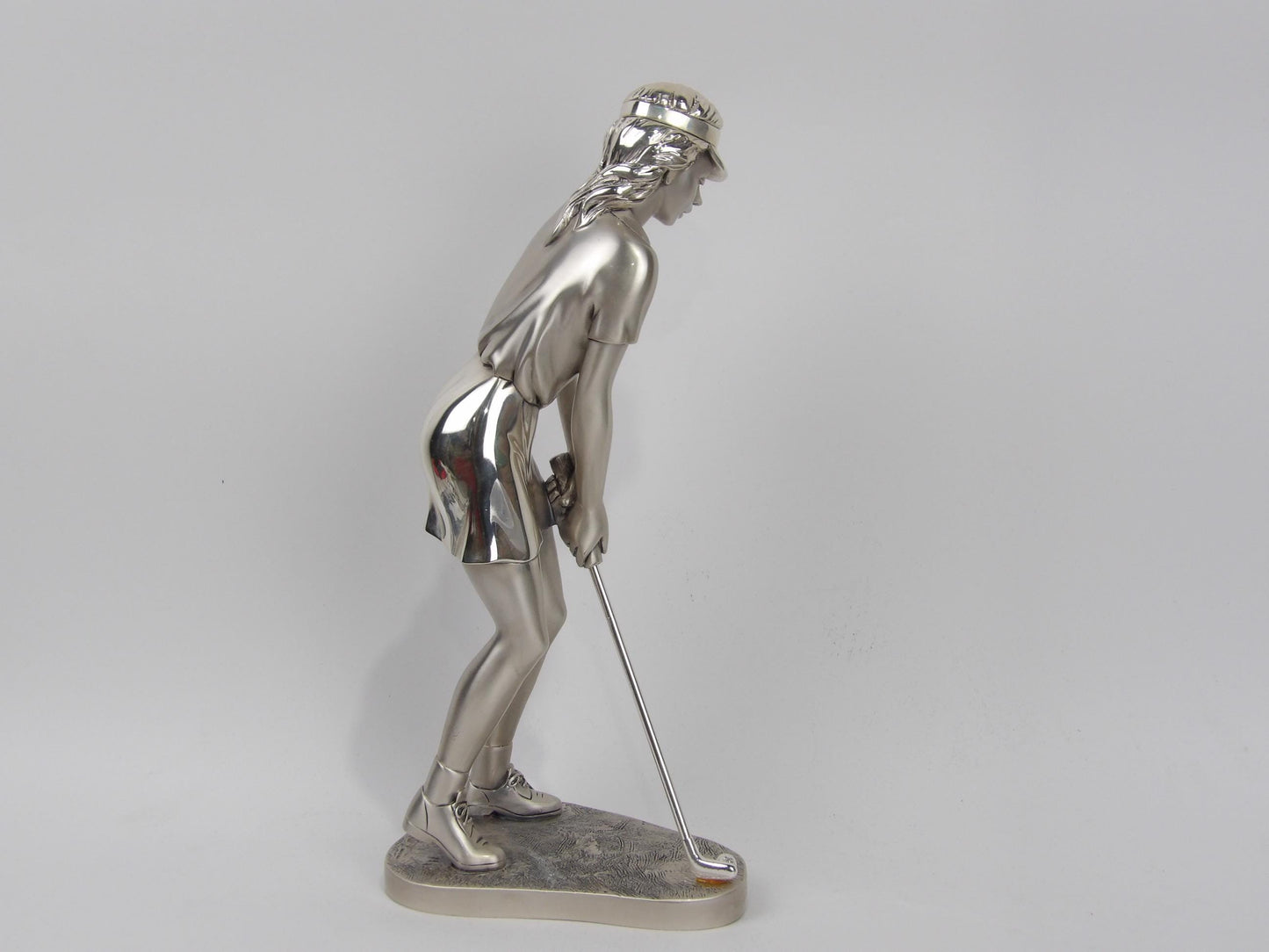 Jugador de golf de resina plateada sobre mármol rojo. Decoración dinámica y elegante.